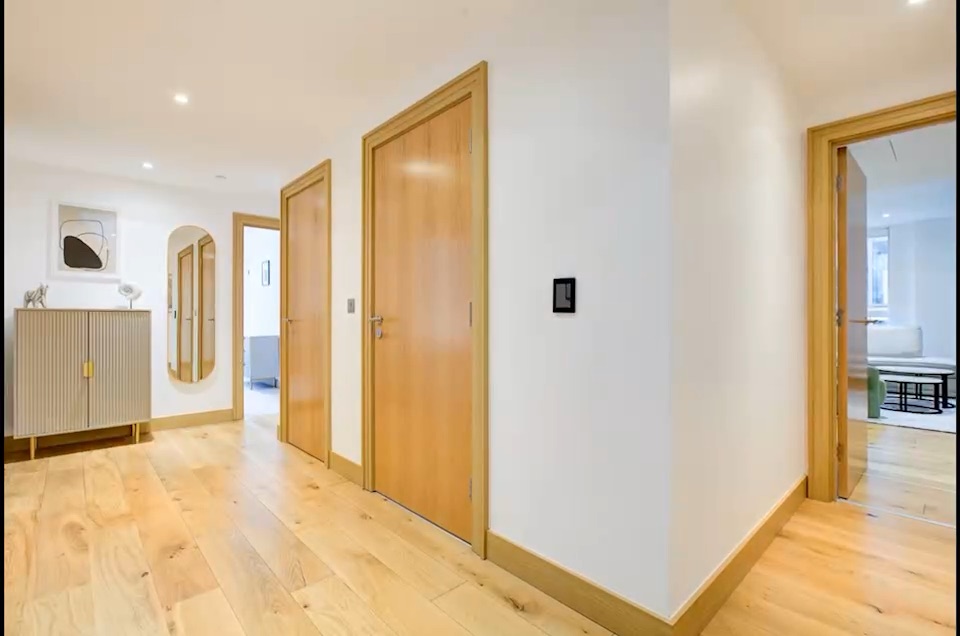 A hallway in oak and white, doors opening off it in sequence.